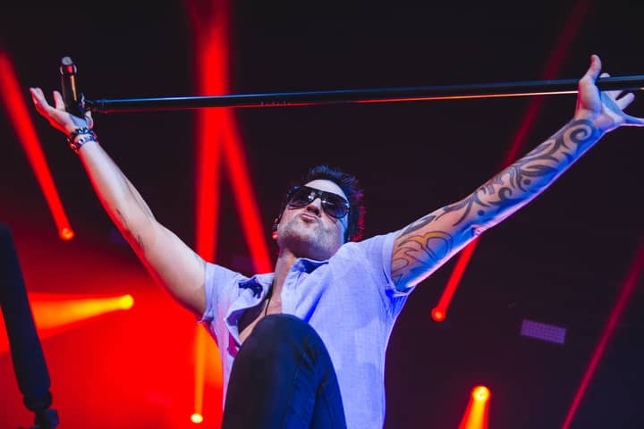Exciting concert moment with a performer holding a microphone stand amidst bright stage lights.
