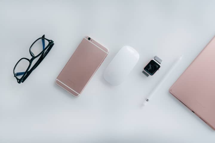 Elegant arrangement of glasses, phone, watch, mouse, pencil, and tablet on a white surface.