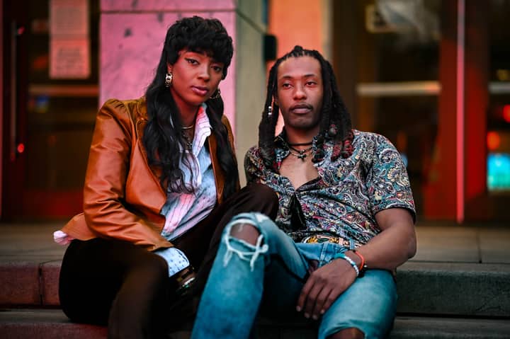 Fashionable couple posing on city streets, showcasing modern urban style in vibrant outfits.