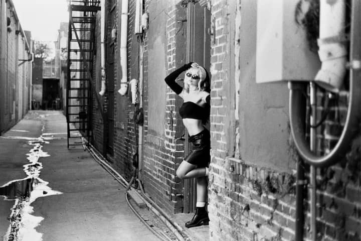 Stylish woman posing in an urban alleyway in black and white.