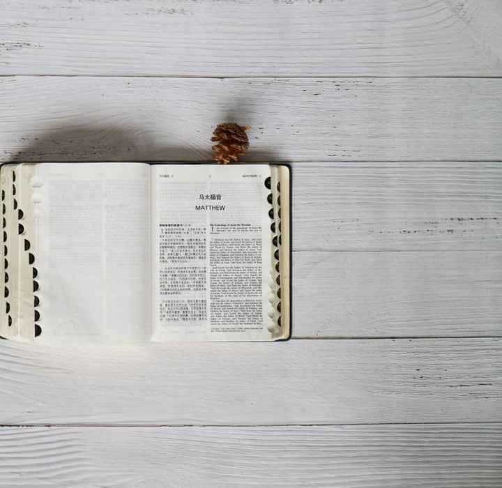 Bible open to Matthew with Mandarin and English text on rustic wood background.