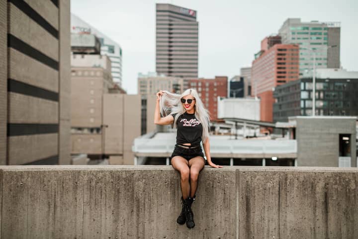 Stylish woman with long blonde hair sitting on a concrete ledge in downtown Cincinnati.