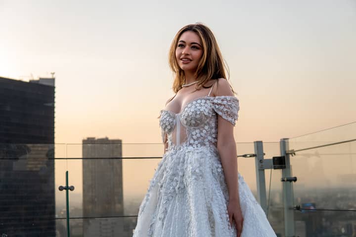 Stunning bride in a white dress with Mexico City skyline at sunset.