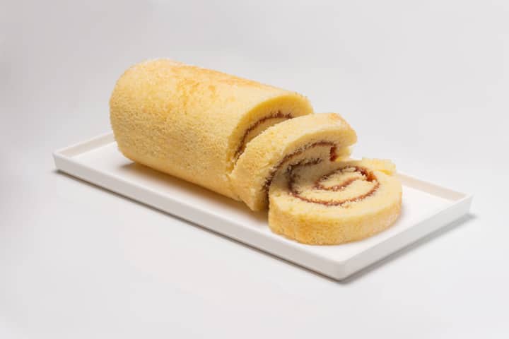 Close-up of a sweet and fluffy vanilla roll cake served on a plate.