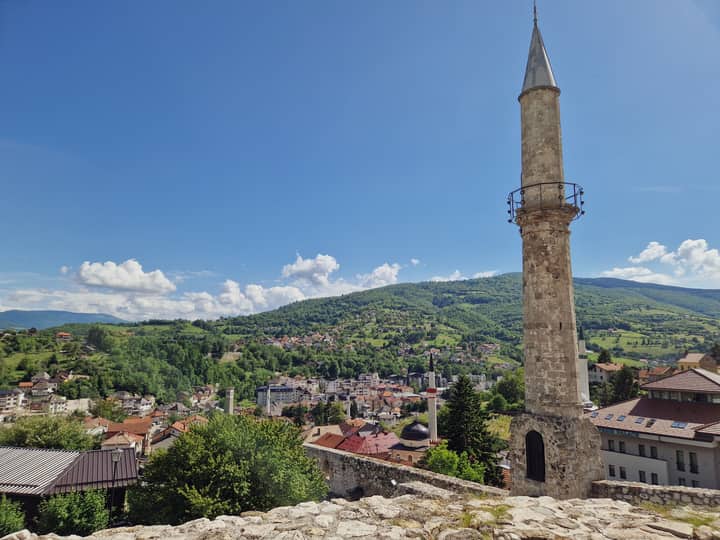 A beautiful scenic view of a Bosnian town featuring a prominent mosque minaret against a clear blue sky.