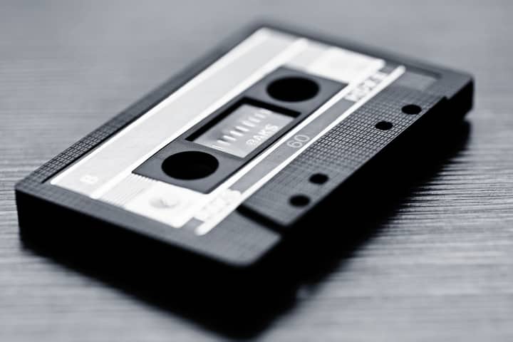 Close-up of a vintage cassette tape on wooden surface in black and white.