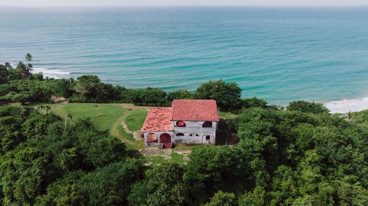 Aerial view of an abandoned house set against the scenic coastline of Patillas, Puerto Rico.