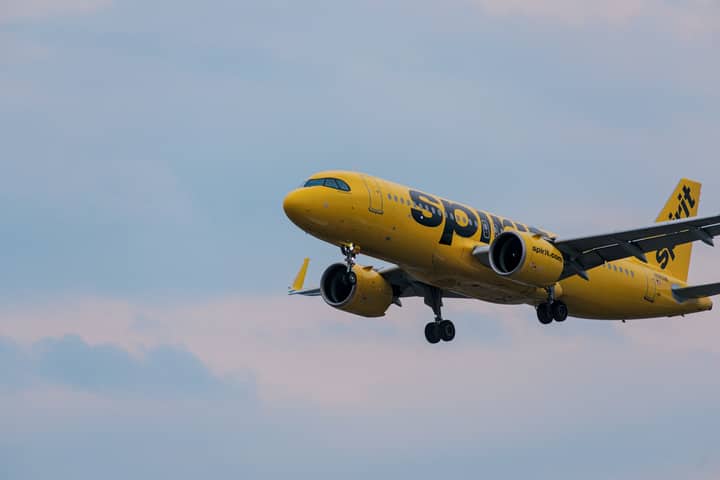 A Spirit Airlines yellow jet in flight over Atlanta, showcasing aviation and travel.