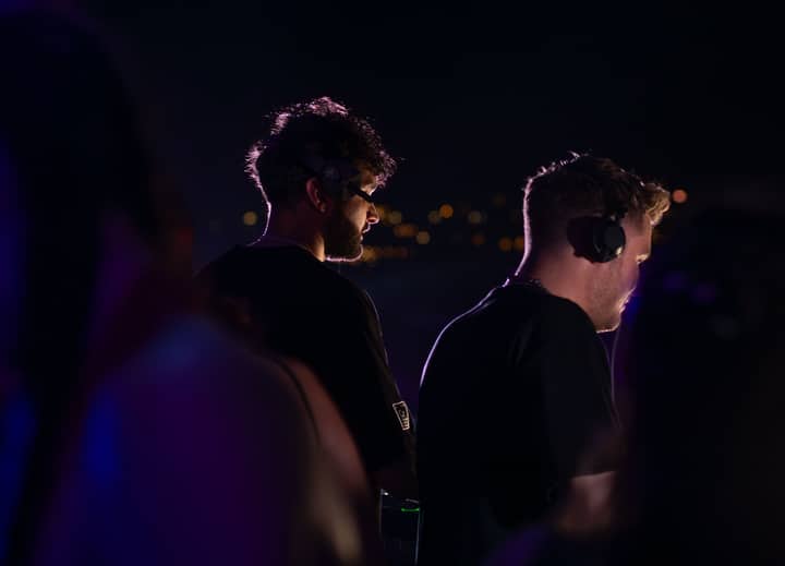 Two DJs wearing headphones performing at a nighttime event in Sozopol, Bulgaria.