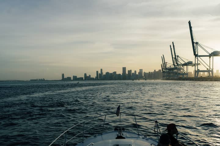 Capture of Miami's skyline and harbor cranes during a tranquil sunset from a boat's deck.