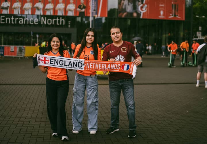 Family posing with England vs Netherlands scarf outside Dortmund stadium for UEFA Euro 2024.