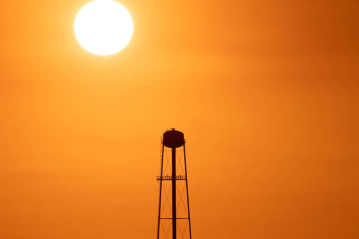 A striking sunset silhouette of a water tower against a vivid orange sky in Mather, CA.