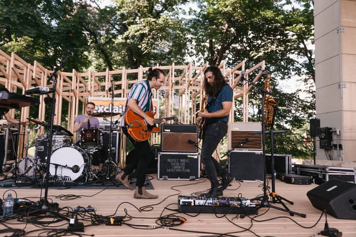 Live band playing on an outdoor stage with drums and electric guitars. Captivating performance.