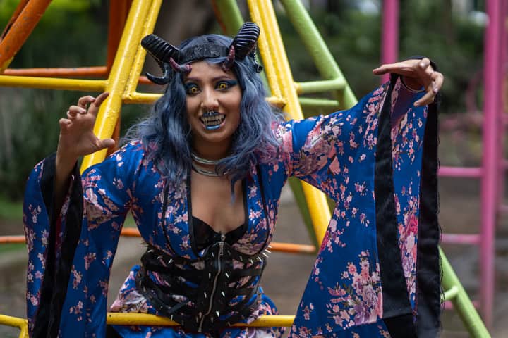 Colorful portrait of a woman in a demon costume posing in a playground.
