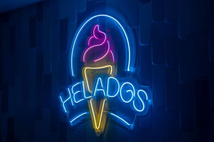 Vibrant neon ice cream sign illuminates a dark wall, creating a lively atmosphere.