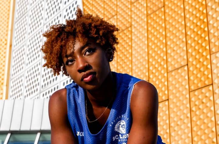 Vibrant portrait of a young woman with afro hairstyle against a modern Berlin backdrop.