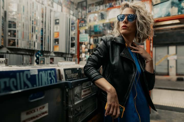 Fashionable woman in leather jacket and sunglasses posing in a vinyl record store in Buenos Aires.