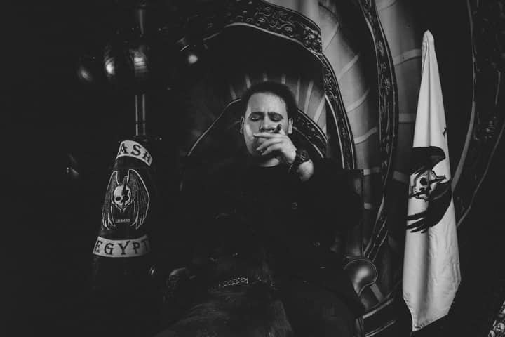 Black and white portrait of a man smoking indoors with a dramatic atmosphere.