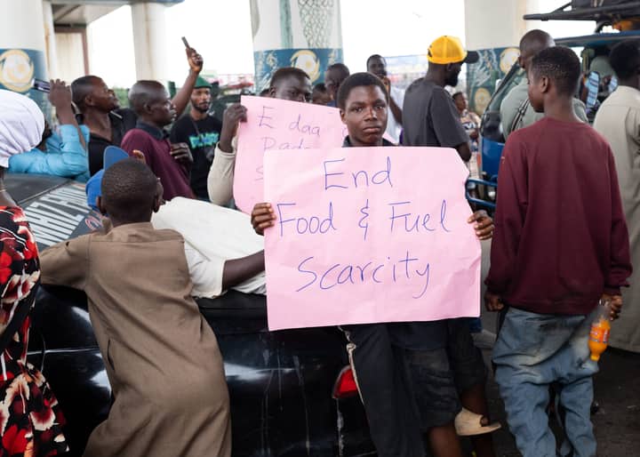 A group of people protest with signs demanding an end to food and fuel scarcity in Nigeria.