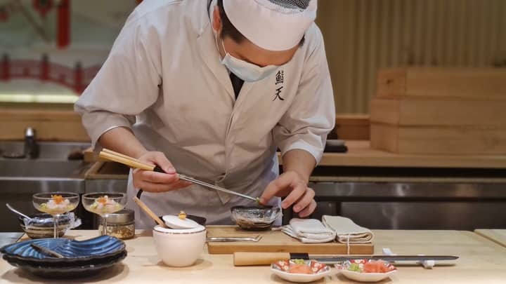 A skilled Japanese chef meticulously prepares sashimi in an intimate restaurant setting.