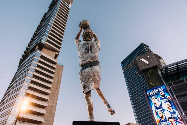 Dynamic statue with basketball skyscraper backdrop showcasing urban architecture.