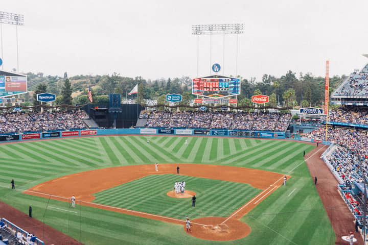Vibrant baseball game at Dodger Stadium with packed stands and players on the field.