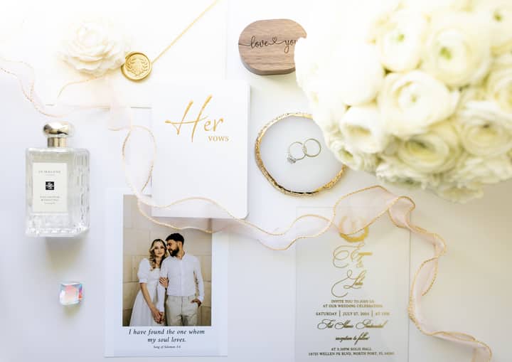 Sophisticated wedding flat lay featuring vows, rings, and florals in a minimalist design.