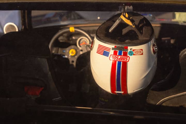 Retro racing helmet hanging in a vintage car interior, evoking classic motorsport style.