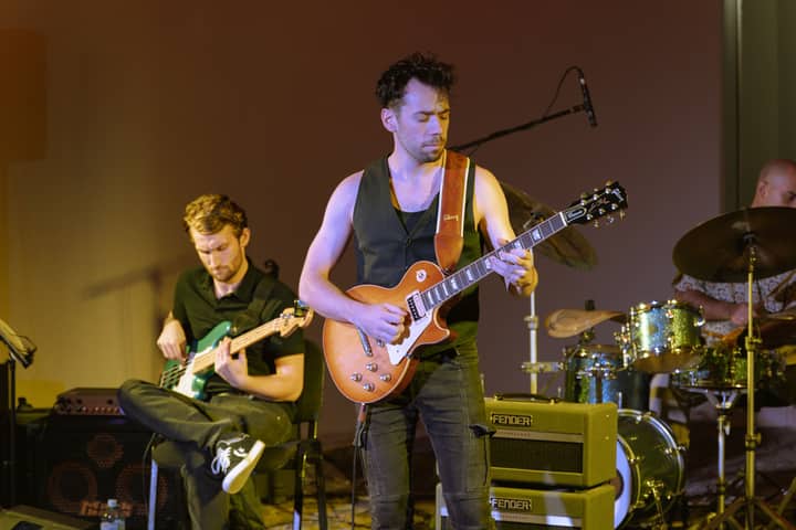 Dynamic live music performance by a band with guitarist, bassist, and drummer on stage.