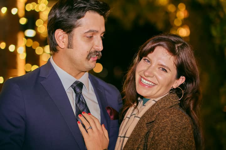 A happy couple enjoying a romantic evening outdoors under festive lights.