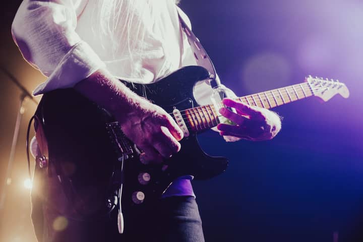 Close-up of a musician passionately playing an electric guitar under stage lights.