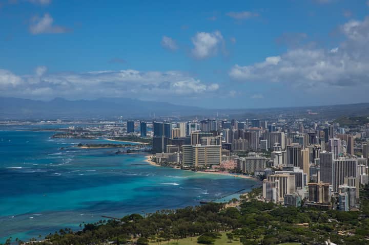 Stunning aerial view of Honolulu's skyline with vibrant ocean hues and lush greenery.