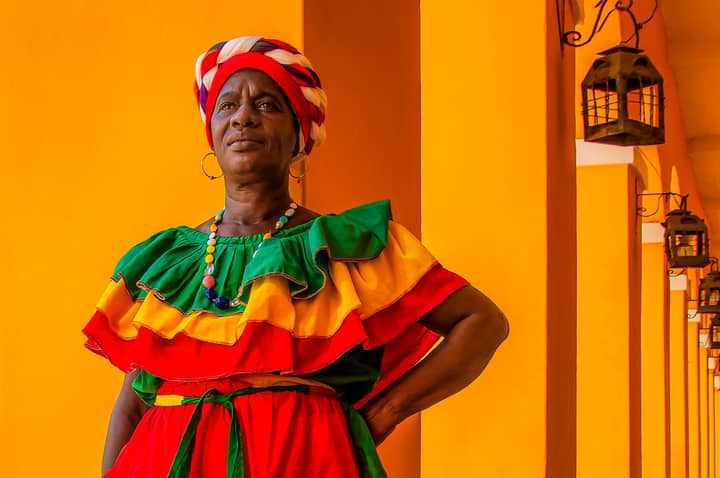 Colorful portrait of a woman in traditional attire against a lively backdrop in Cartagena, Colombia.