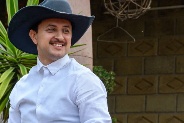 Portrait of a smiling man in a cowboy hat outdoors, exuding warmth and style