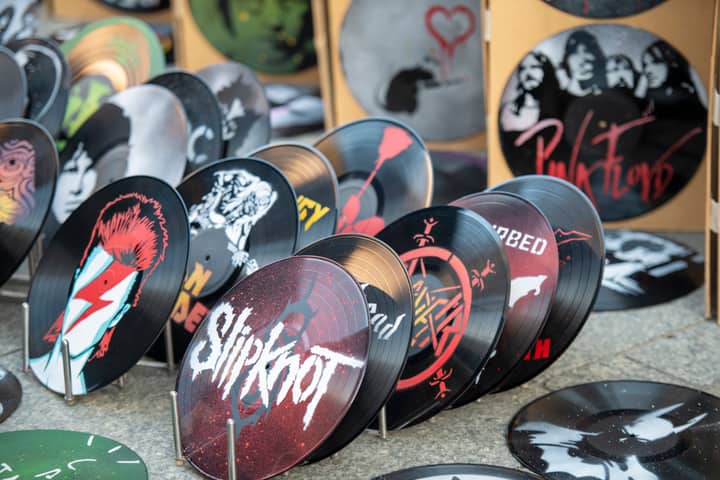 Collection of artistic vinyl records featuring iconic band designs on display at market.