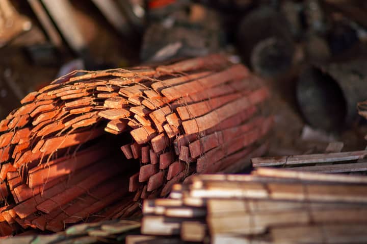 A close-up view of stacked red wooden planks in a dimly lit warehouse.