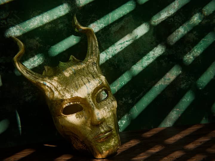 Close-up of an aged, horned mask with shadows, evoking mystery and history.