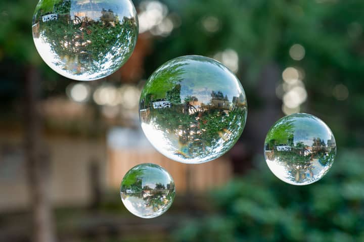 Transparent glass spheres reflect a garden scene, creating a surreal optical illusion.