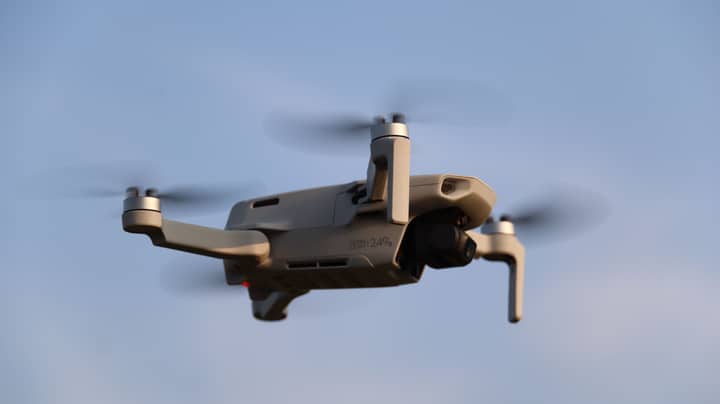 A compact drone flying seamlessly in a clear blue sky, showcasing modern technology.