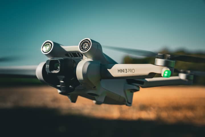 Detailed shot of a Mini 3 Pro drone flying outdoors, showcasing its camera and design.