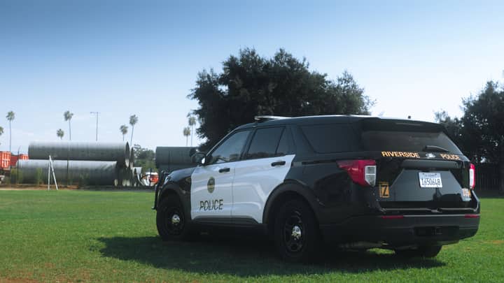 Black and white Riverside Police SUV parked in a sunny grassy area.