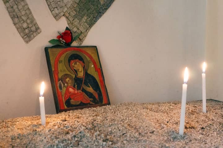 A serene setup with a religious icon and candles in sand creating a peaceful atmosphere.