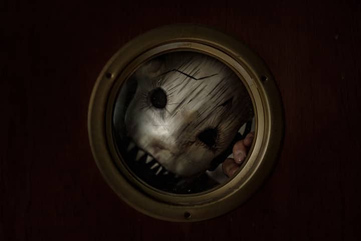 Creepy masked figure looking through a porthole, creating a chilling and eerie Halloween vibe.