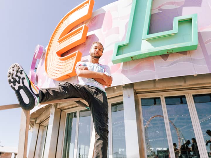 Dynamic portrait of a man posing under the colorful Coney Island sign in New York City.