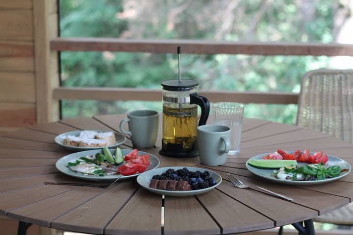 Casual breakfast with berries, veggies, and tea on a wooden porch table.