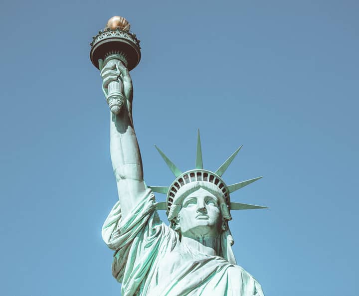 Close-up of the iconic Statue of Liberty against a clear blue sky, symbolizing freedom in New York City.