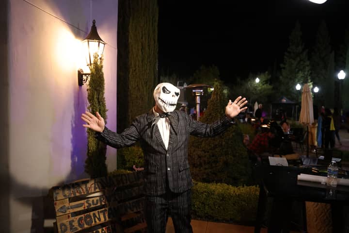 A person in a Halloween costume outdoors at night, celebrating lively festivities.