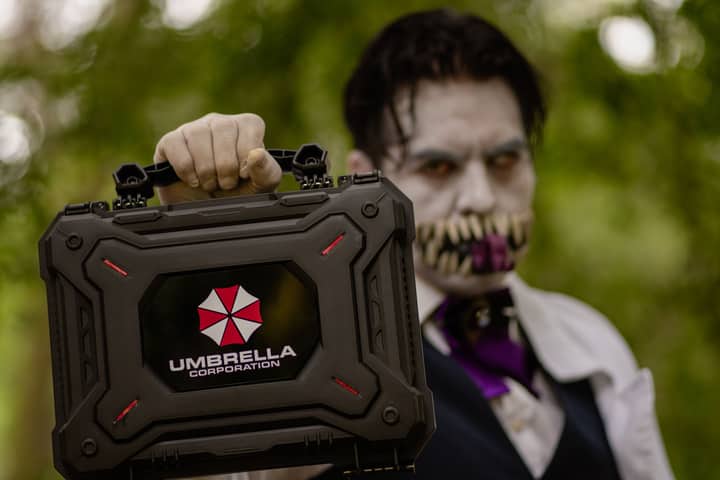 A cosplayer holding an Umbrella Corporation case, inspired by Resident Evil, ready for Halloween.