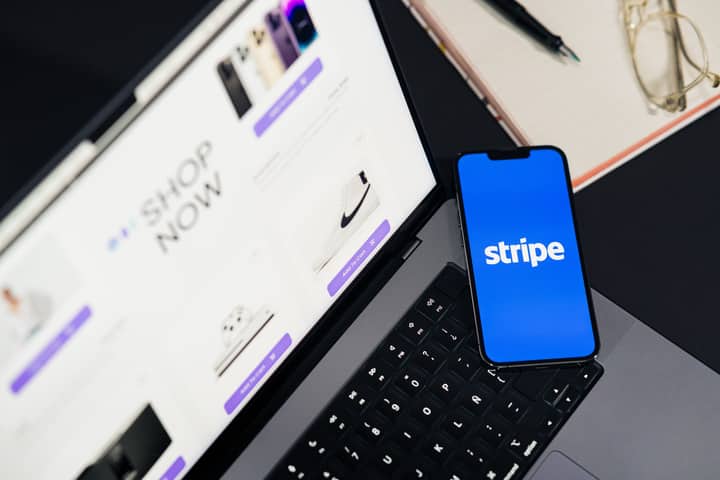Mobile phone displaying Stripe app on a laptop with an eCommerce site open, symbolizing online shopping.