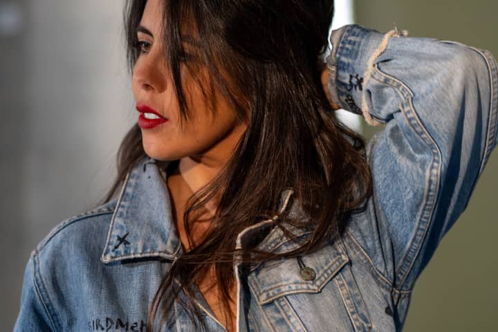 Confident woman with red lips posing in a denim jacket, showcasing modern fashion style.